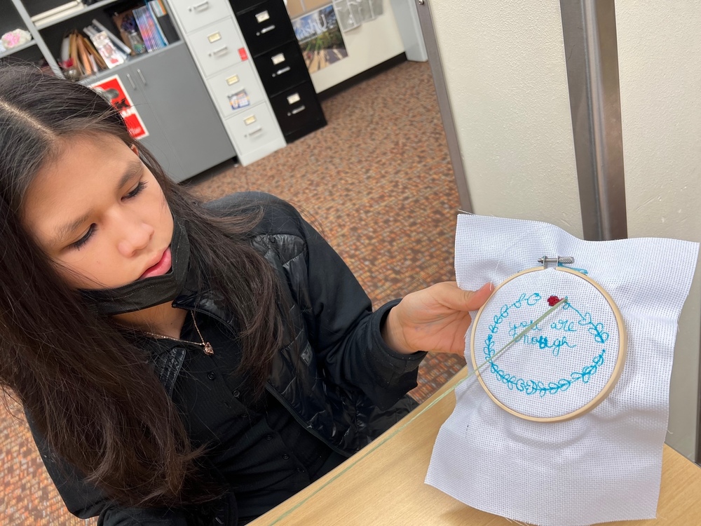student holding up her cross stitch work