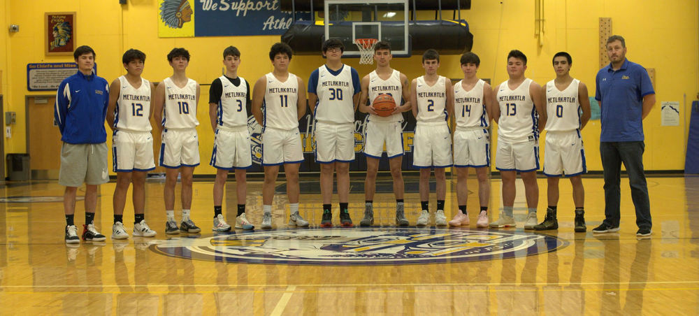 Chiefs 2021 basketball team and coaches stand on their home court.