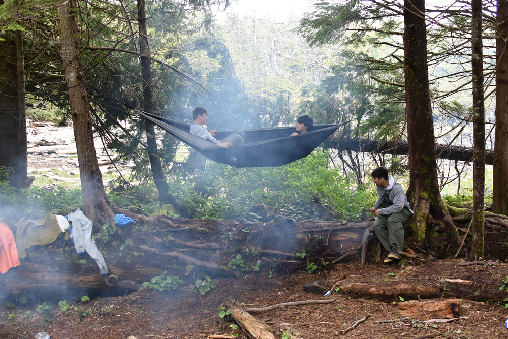 students in a hammock with smoke from a campfire