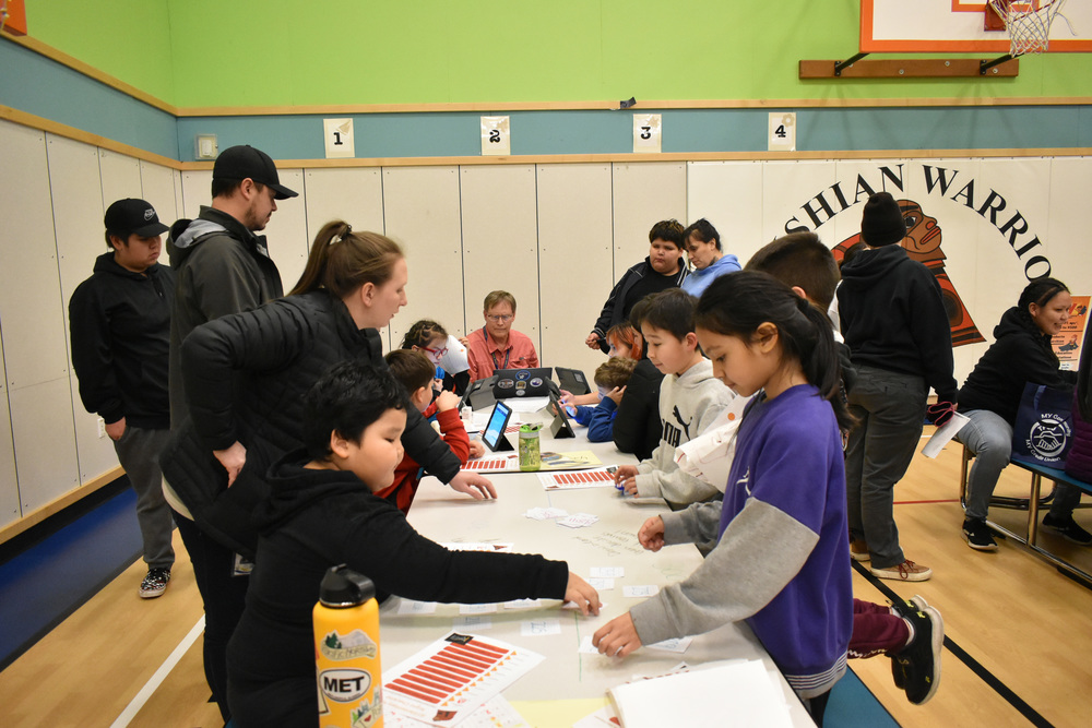 students and adults  leaning over table playing math games