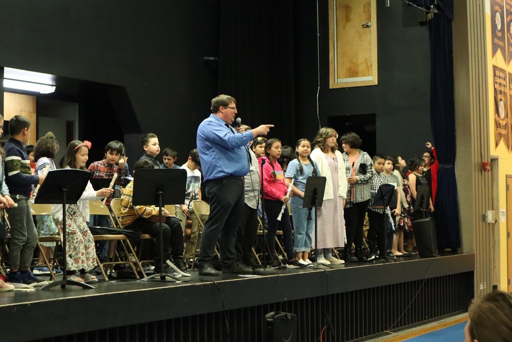Students and teacher on stage after performing a band concert