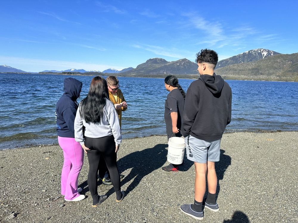 students and teacher at beach collecting algae