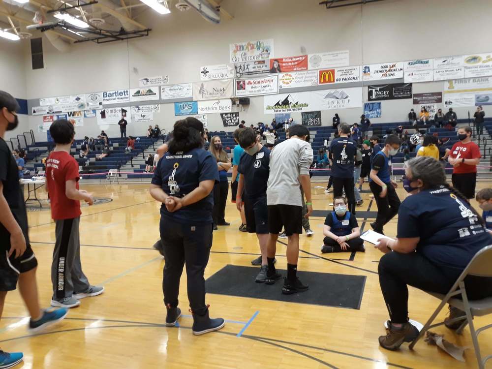Students competing in NYO event stick pull in a gym surrounded by onlookers