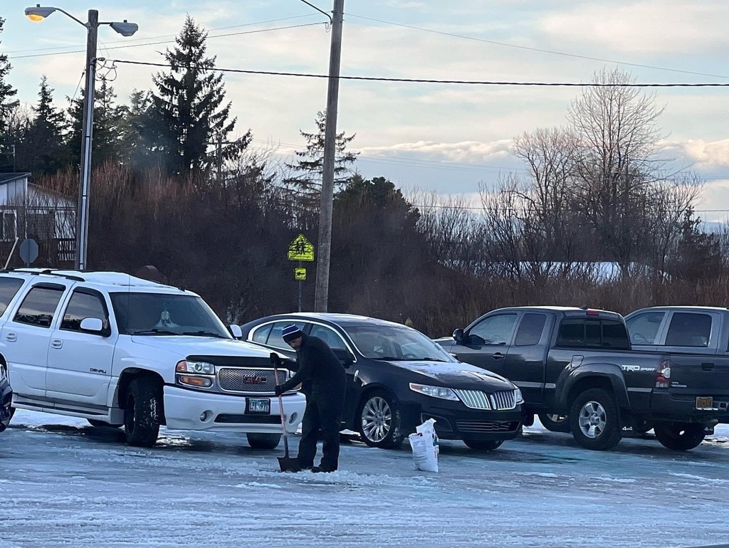 Superintendent Taw Lindsey lays salt on the parking lot on the school campus.