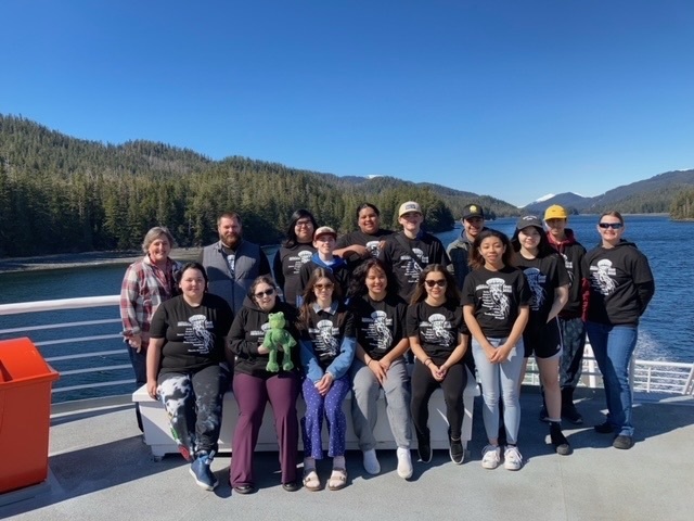 students sitting on a ferry with chaperones