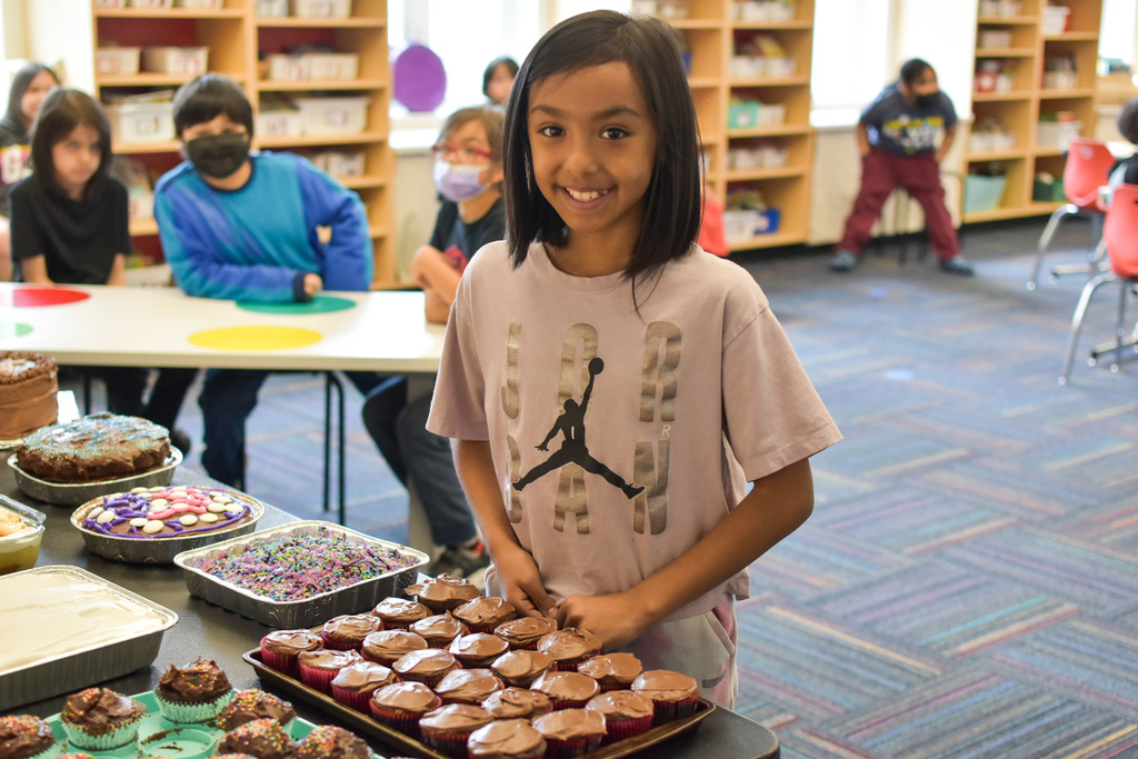 a student standing by cupcakes she made