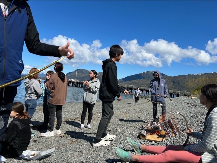 students roasting s’mores on the beach