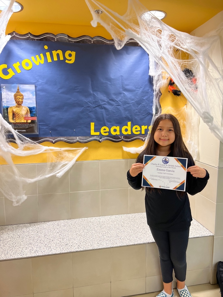 Picture of student holding a certificate next to a sign that says growing leaders