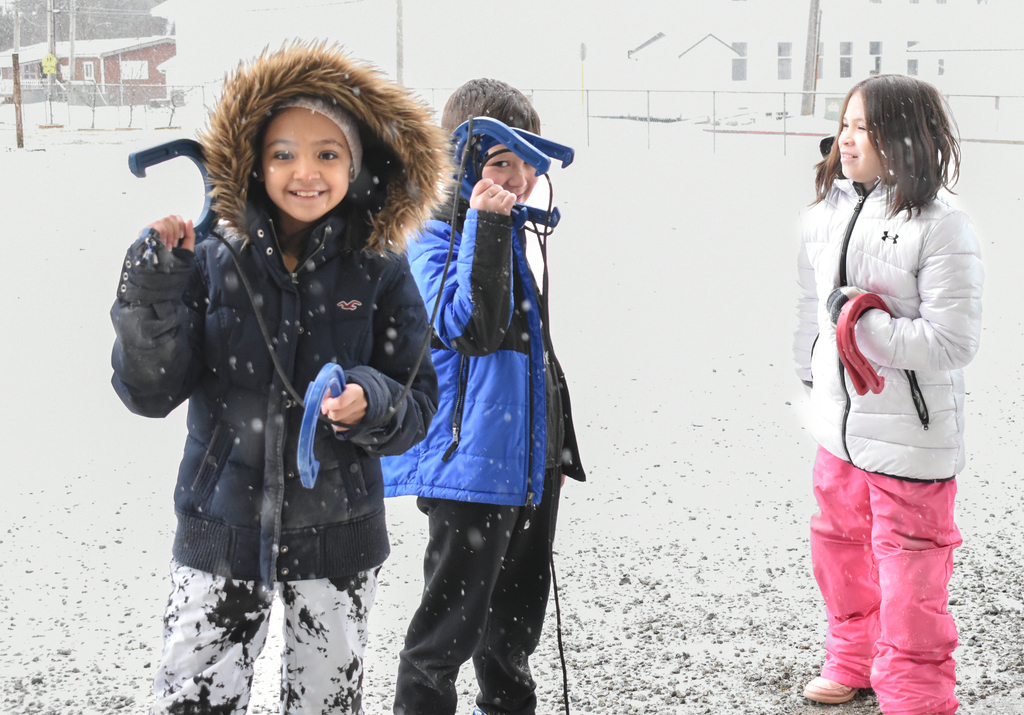 students smiling at camera in coats during snow