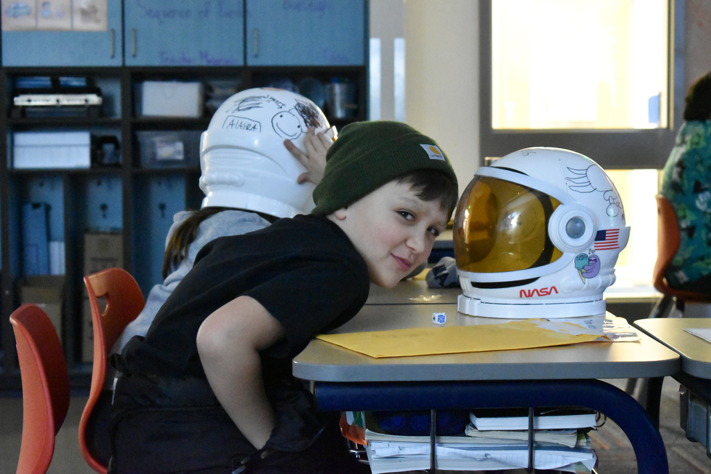 a student smiling next to his space helmet