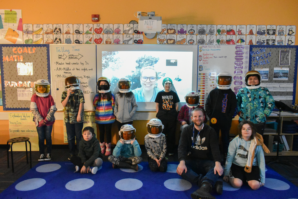 students smiling at camera with space helmets on