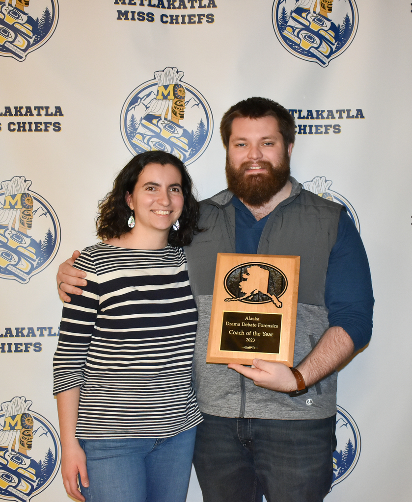 adults smiling holding a plaque in front of a backdrop