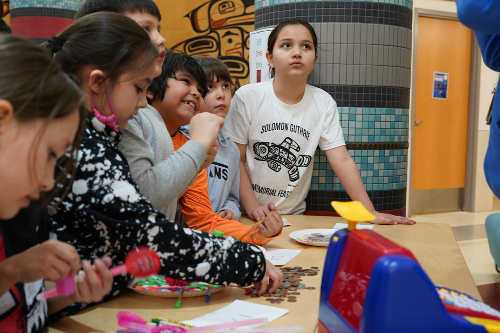 students at table with coins