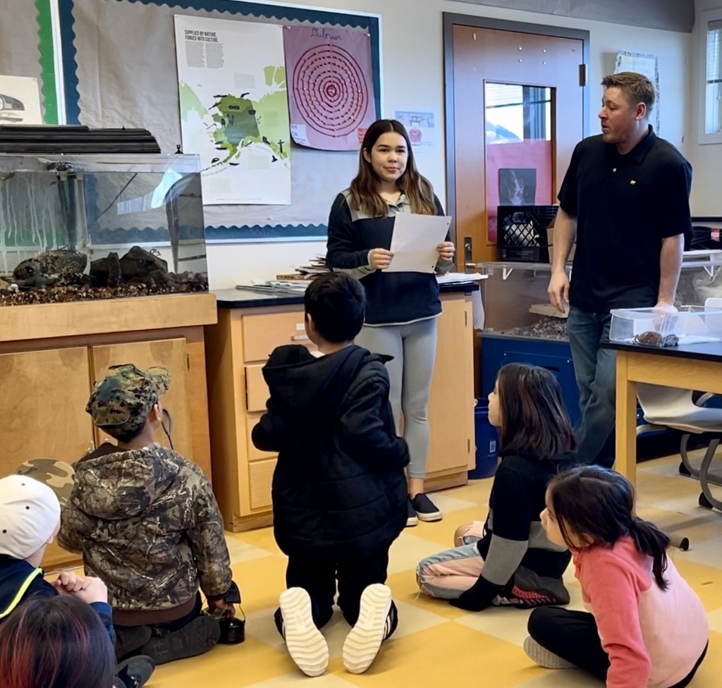HS student presenting to younger students in science classroom