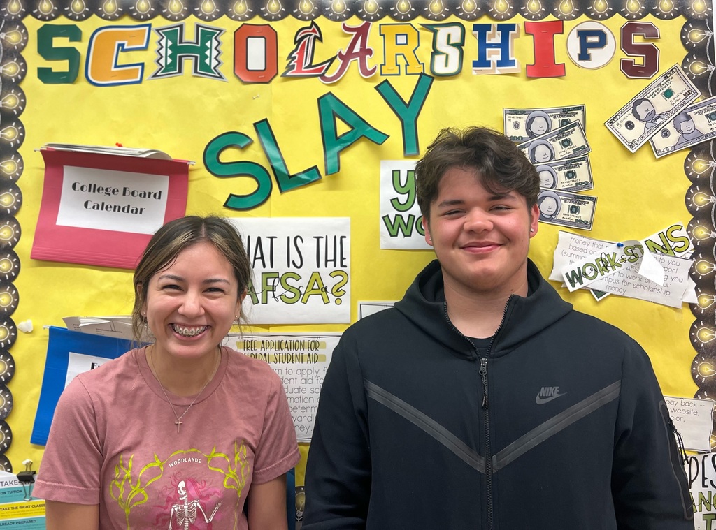 picture of students smiling in front of a bulletin board
